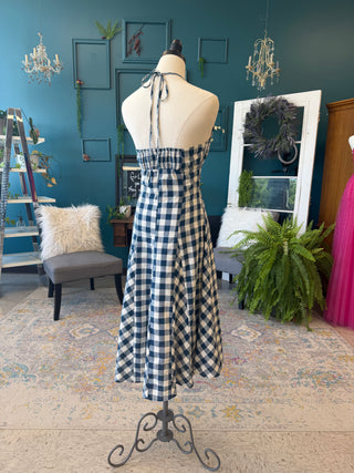 Mannequin wearing a blue and white checkered dress in a room with decorative elements.