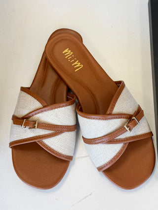 Pair of sandals with brown straps and soles on a light background